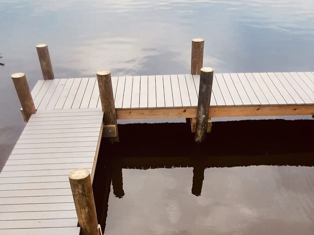 A finished light-decked pier standing over still water.